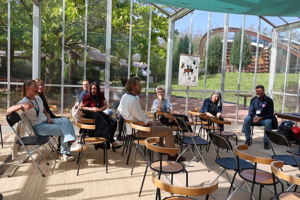 Een sessie in de kas, met de stoelen in een kring en uitzicht op de tuin
