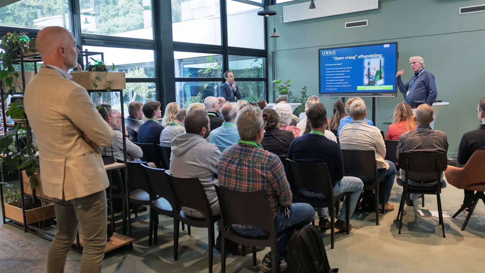 Volle zaal tijdens de Gebruikersdag, met een presentatie op het scherm