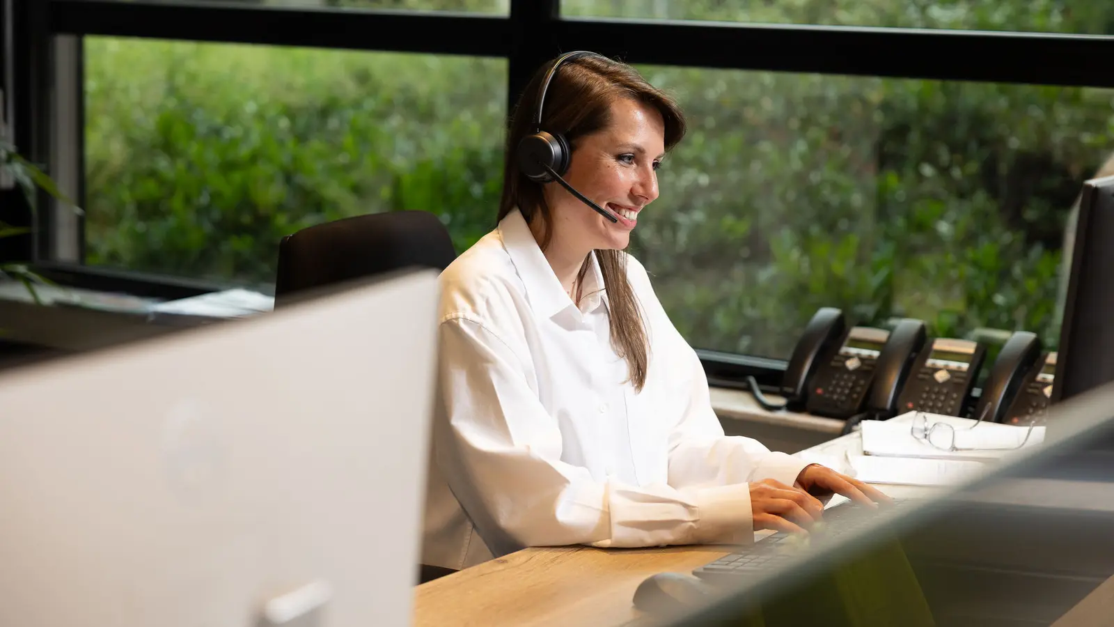 Een medewerker met headset achter het scherm in het klantcontactcentrum