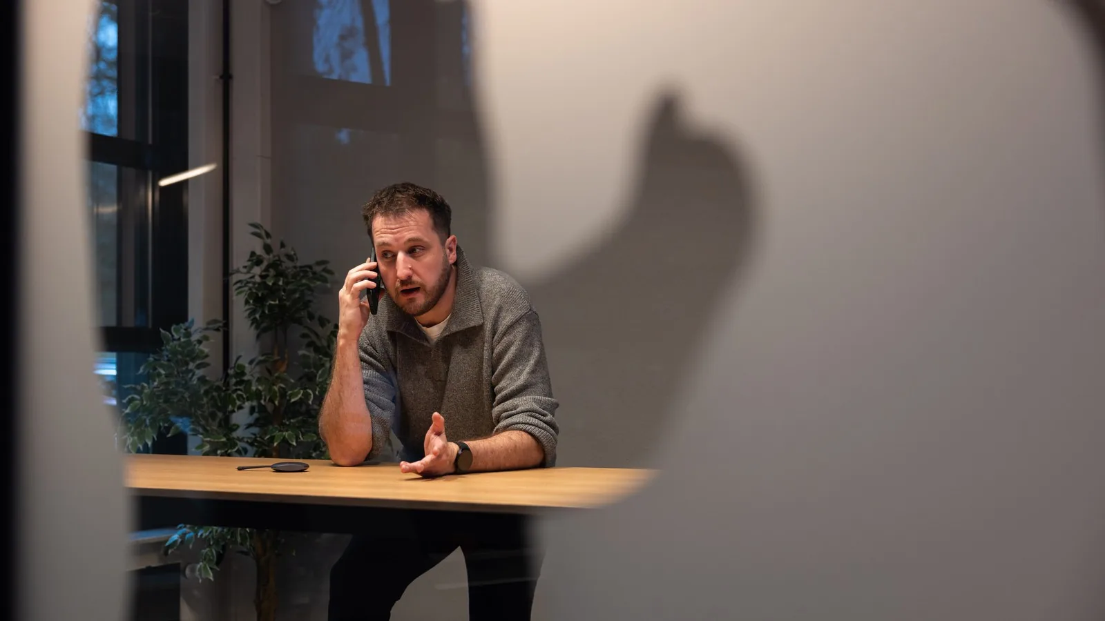 Medewerker met de telefoon aan het oor, staand aan een hoge tafel