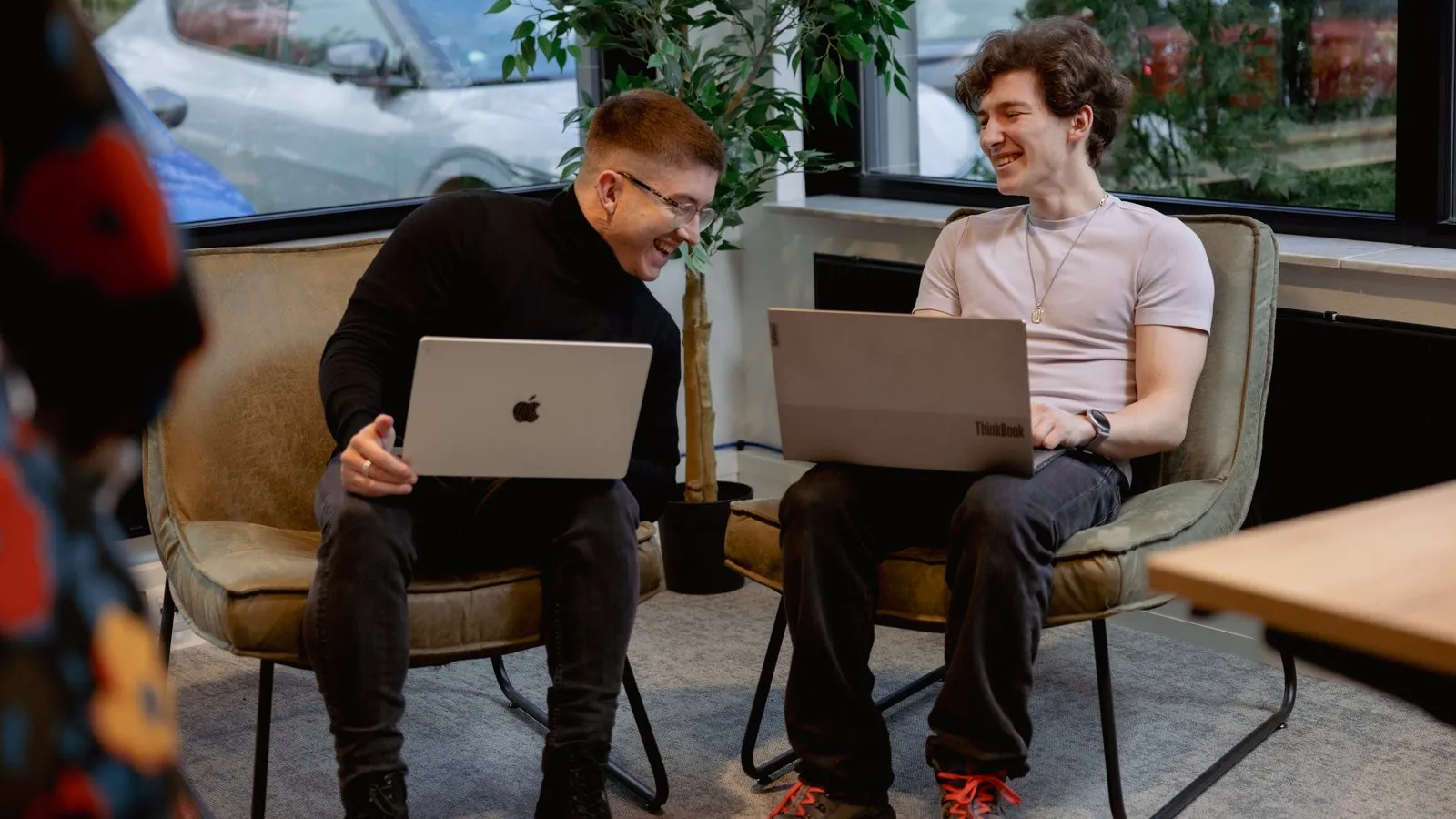 Twee collega’s van Unexus met laptops in de zithoek