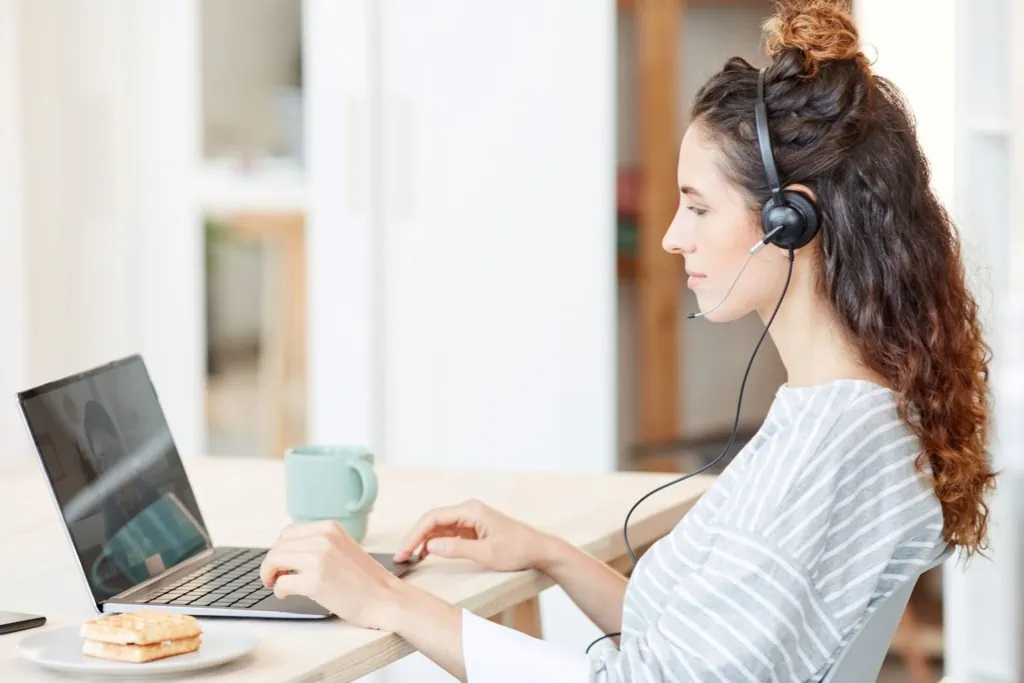 modern-young-caucasian-woman-wearing-headset-working-laptop-home-horizontal-side-view-shot