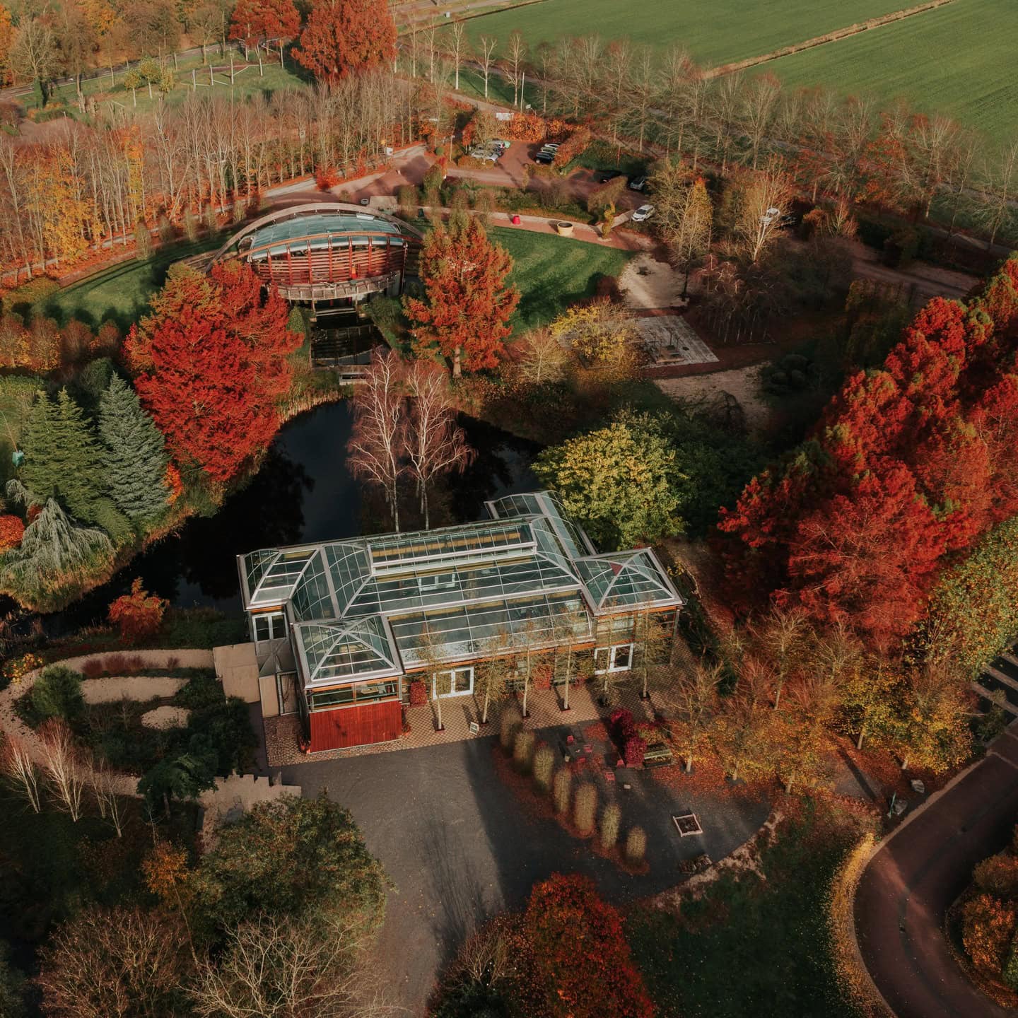 Luchtfoto van de Rijkskwekerij in herfstkleuren, met de twee oranjerieën tussen het bos